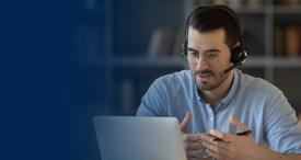Man with headset talking and looking at laptop